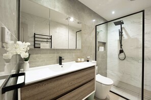 A modern bathroom with a marble vanity, a large mirror, a shower enclosure, and a toilet. - 5BR Family Retreat Spa, Sauna, Gym Miranda sleep12 (Miranda)