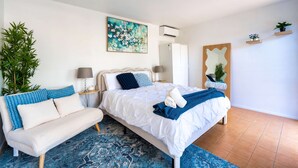 Een slaapkamer met een bed, nachtkastjes, een lamp, een potplant, een schilderij en een spiegel.