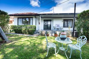 A residential house with a front porch, a small garden, and outdoor seating. - 5BR Family Retreat Spa, Sauna, Gym Miranda sleep12 (Miranda)