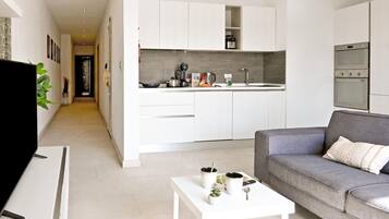 A modern kitchen with white cabinetry, a built-in oven, and a countertop with various appliances.