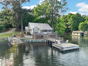 A lakeside cabin with a dock, a covered deck, and a small boathouse.