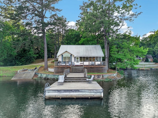 A lakeside cabin with a dock, surrounded by trees.