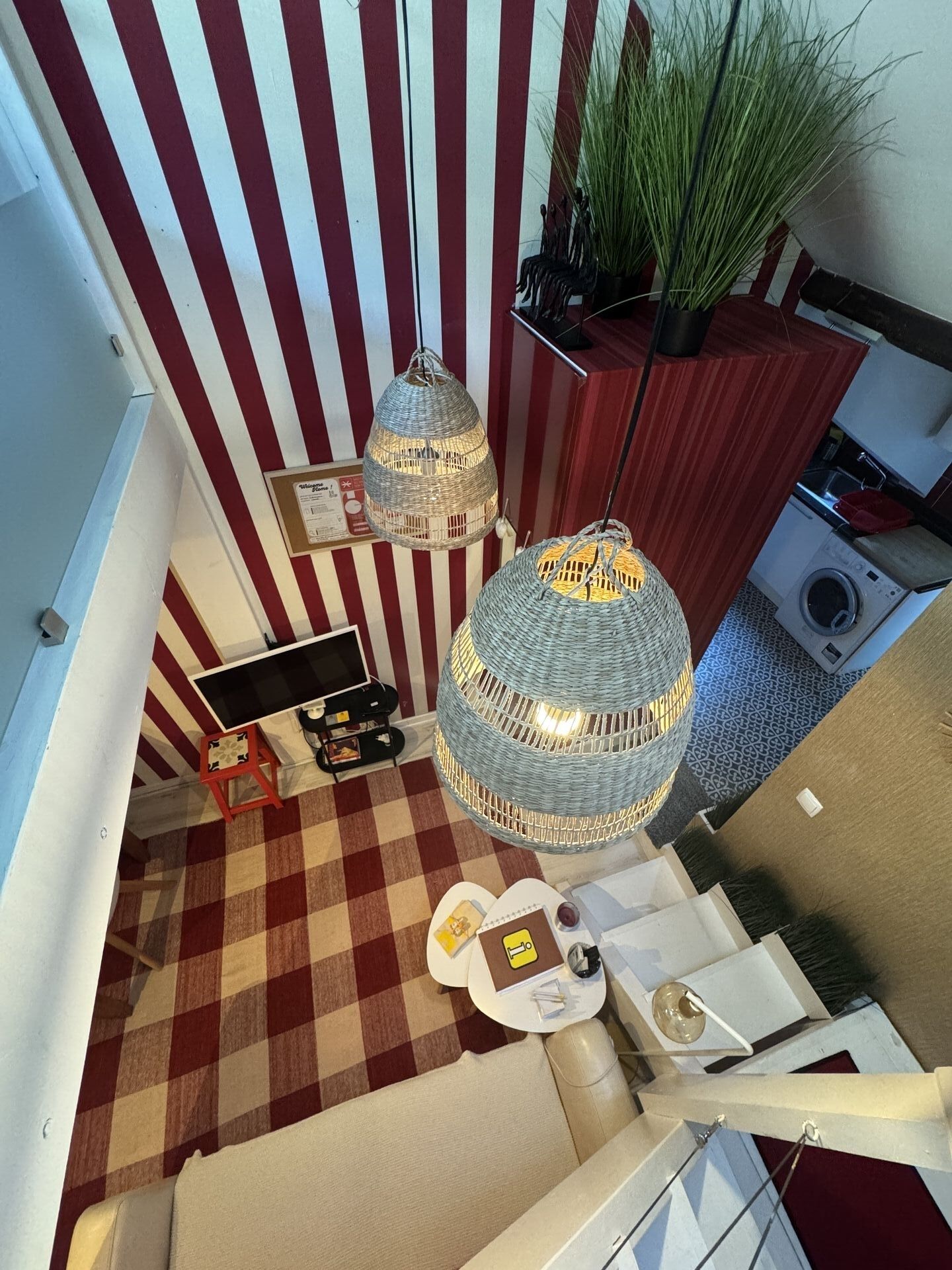 A staircase with a checkered floor, a red and white striped wall, and a hanging light fixture.