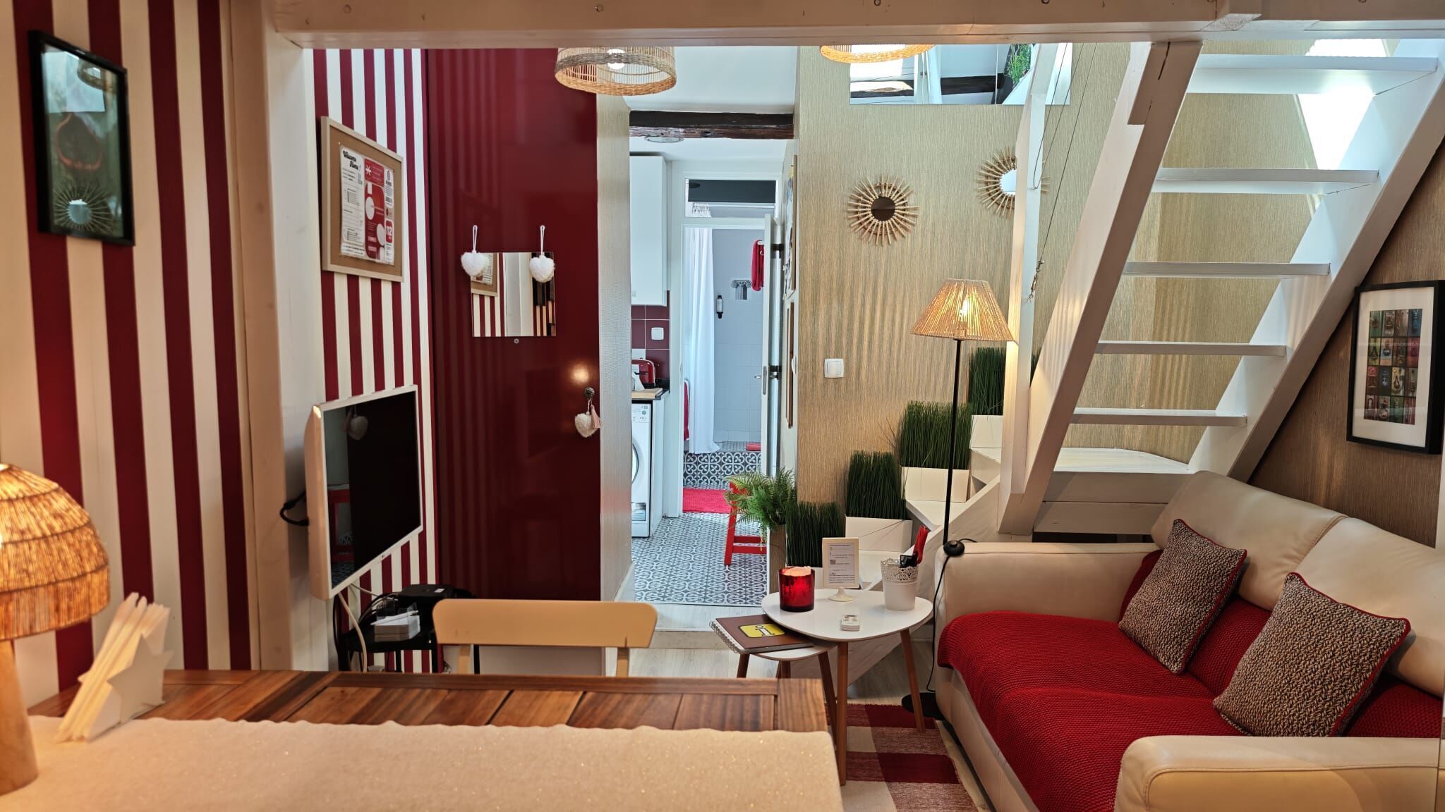 A modern interior with a sofa, a dining table, and a kitchen visible through an open door.