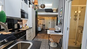Een kleine keuken met een spoelbak, fornuis en een eetgedeelte met stoelen.