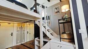 Een hotelinterieur met een trap, een spiegelwand en een klein plankje met een lamp en een mand.