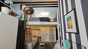 Een compacte leefruimte met een vide, een kitchenette en een eethoek.