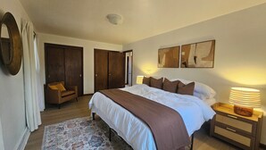 A bedroom with a large bed, a chair, a nightstand, and a rug. - Serene 4-bedroom house with brook and forest in charming Racine (Racine)
