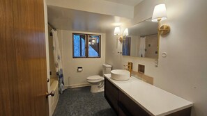 Un baño con ducha, inodoro, lavabo y ventana.