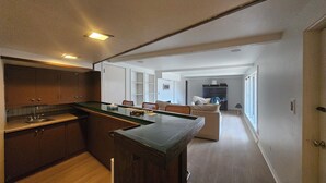 A modern kitchen with a central island, wooden cabinets, and a built-in sink. - Serene 4-bedroom house with brook and forest in charming Racine (Racine)