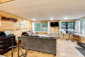 A cozy cabin interior with a sofa, a TV, and a dining area.