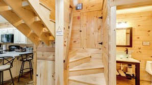 Un intérieur en bois comprenant un espace cuisine, un escalier et une salle de bain.