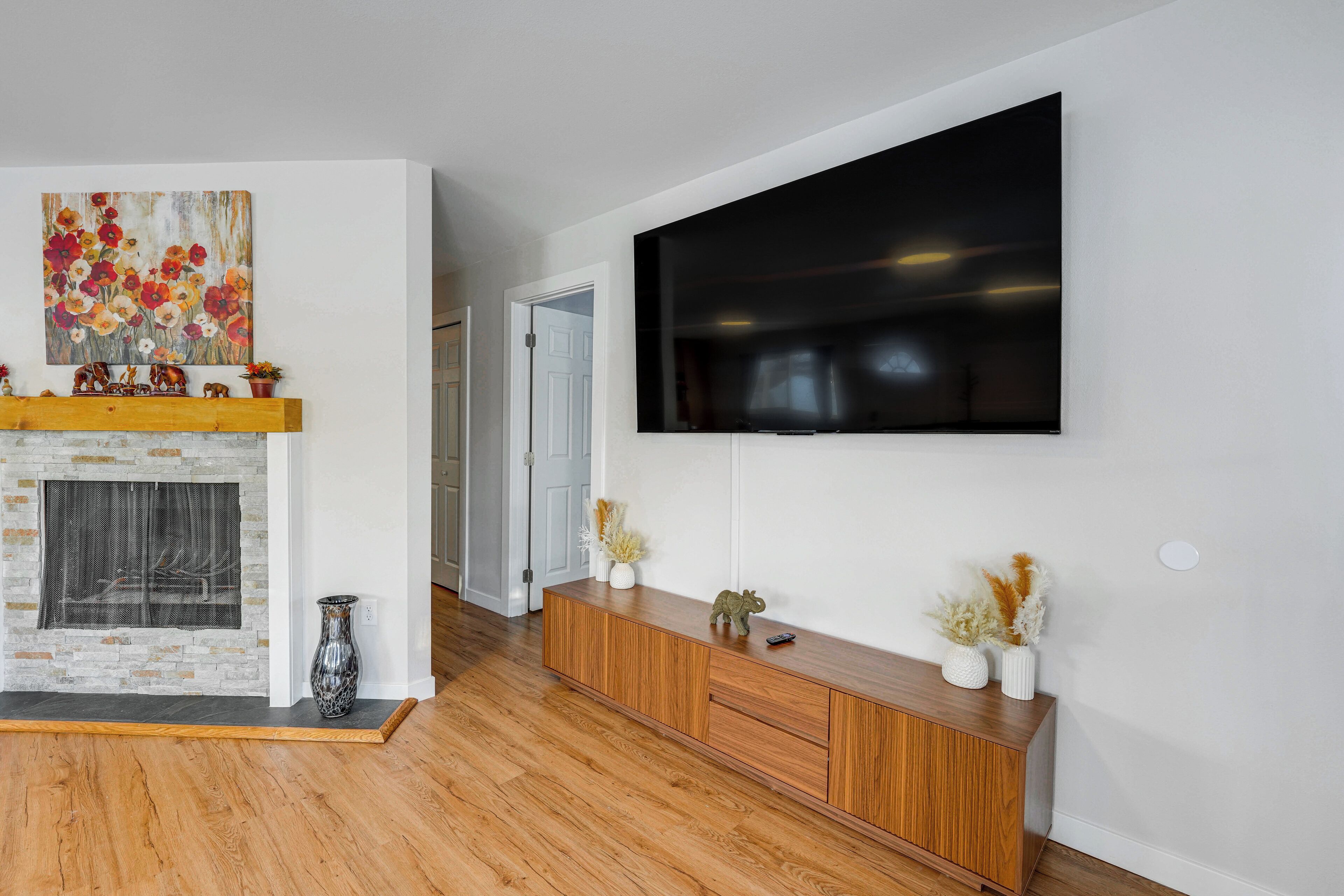 A living room with a fireplace, a mounted TV, and a wooden entertainment unit.