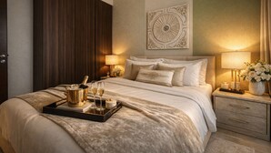 Et hotelværelse med en stor seng, et sengebord med lampe, et dekorativt vægmaleri og et fad med champagneglas og en flaske.