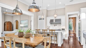Una cocina amplia con una mesa de comedor de madera, lámparas colgantes y una campana extractora de acero inoxidable.