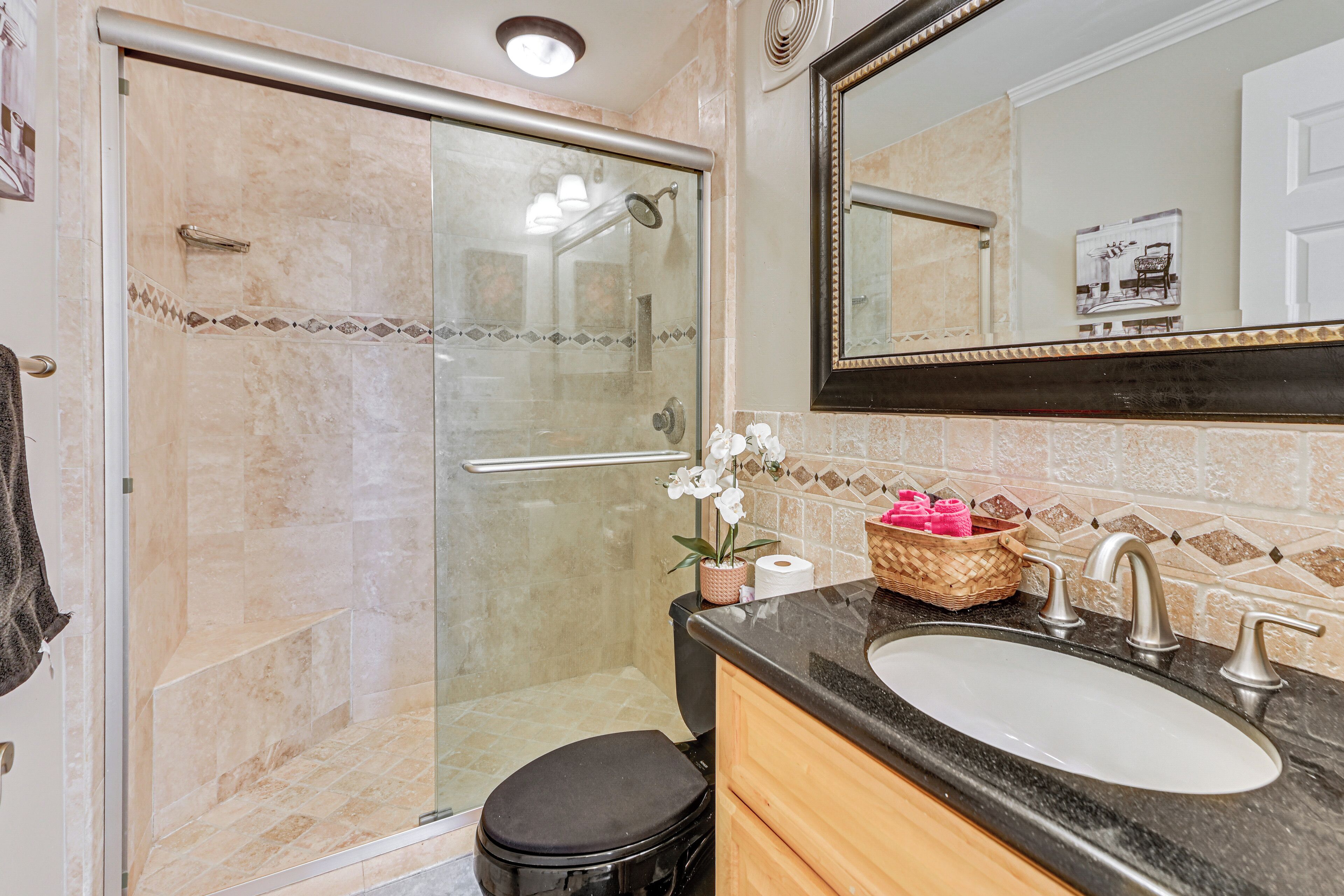 Une salle de bain avec une douche à parois de verre, un lavabo avec un miroir et des toilettes.