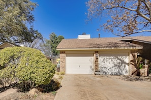 A residential house with a garage, a driveway, and a large tree in the front yard. - 6 Mi to Texas Tech: Studio w/ Shared Pool & Grill (Lubbock)