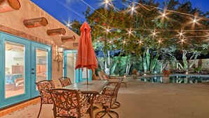 An outdoor patio with a table and chairs, a wooden deck, and string lights. - 6 Mi to Texas Tech: Studio w/ Shared Pool & Grill (Lubbock)