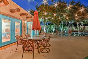 An outdoor patio with a table and chairs, a wooden deck, and string lights. - 6 Mi to Texas Tech: Studio w/ Shared Pool & Grill (Lubbock)