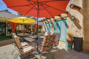 An outdoor patio with a table and chairs, a red umbrella, and a blue door. - 6 Mi to Texas Tech: Studio w/ Shared Pool & Grill (Lubbock)