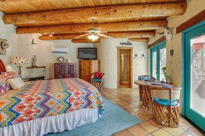 A bedroom with a large bed, a ceiling fan, a television, and a dining area with wicker furniture. - 6 Mi to Texas Tech: Studio w/ Shared Pool & Grill (Lubbock)