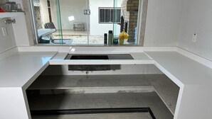 A modern bathroom with a white vanity, a glass shower enclosure, and a visible outdoor area with a bench and a water dispenser. - Casa Sol e Sal is the beach house with a pool for your family. (Prado)
