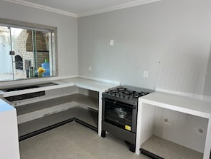 A kitchen with a gas stove, oven, and a window overlooking a brick wall.