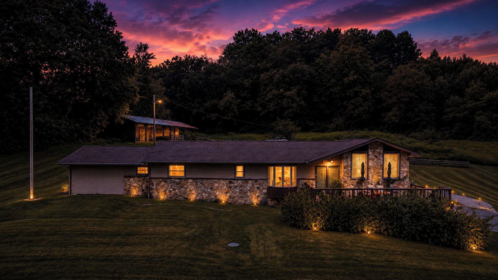 A two-story house with a stone facade, a large deck, and a well-lit front porch.