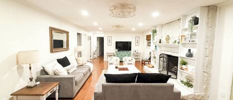 A living room with a sofa, a coffee table, a TV, and a fireplace.