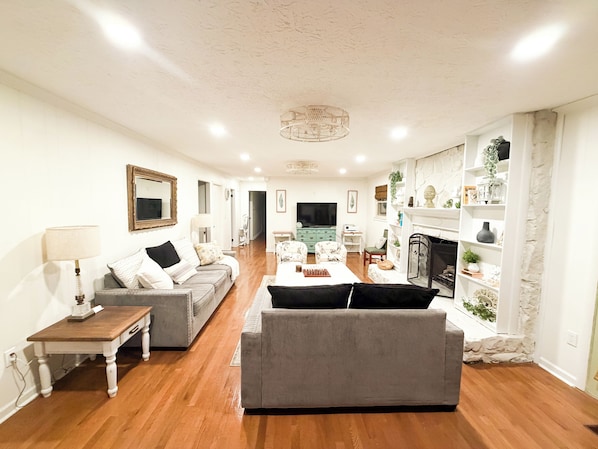 A living room with a sofa, a coffee table, a TV, and a fireplace.
