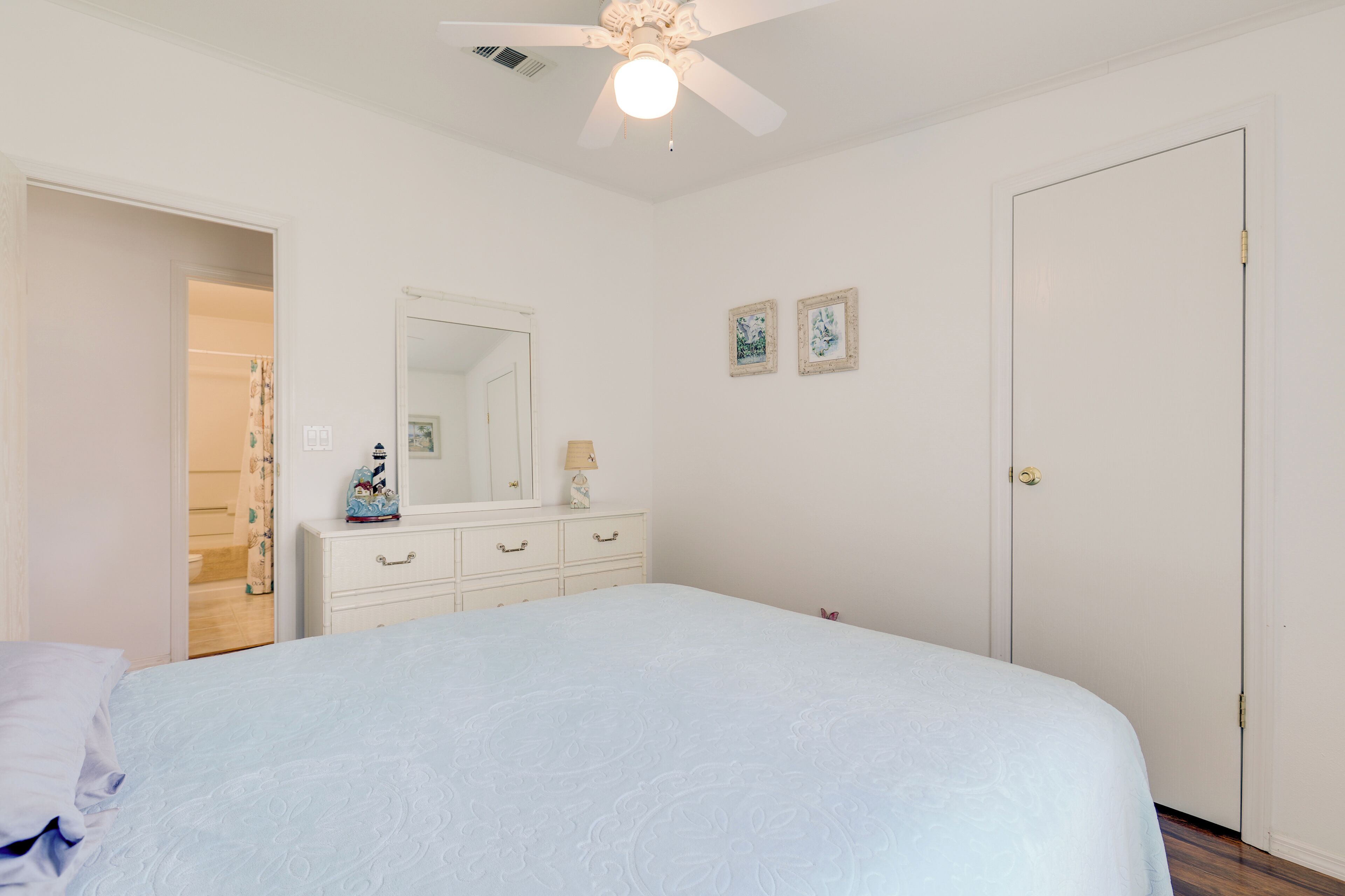 A bedroom with a bed, a dresser, a mirror, and a door.