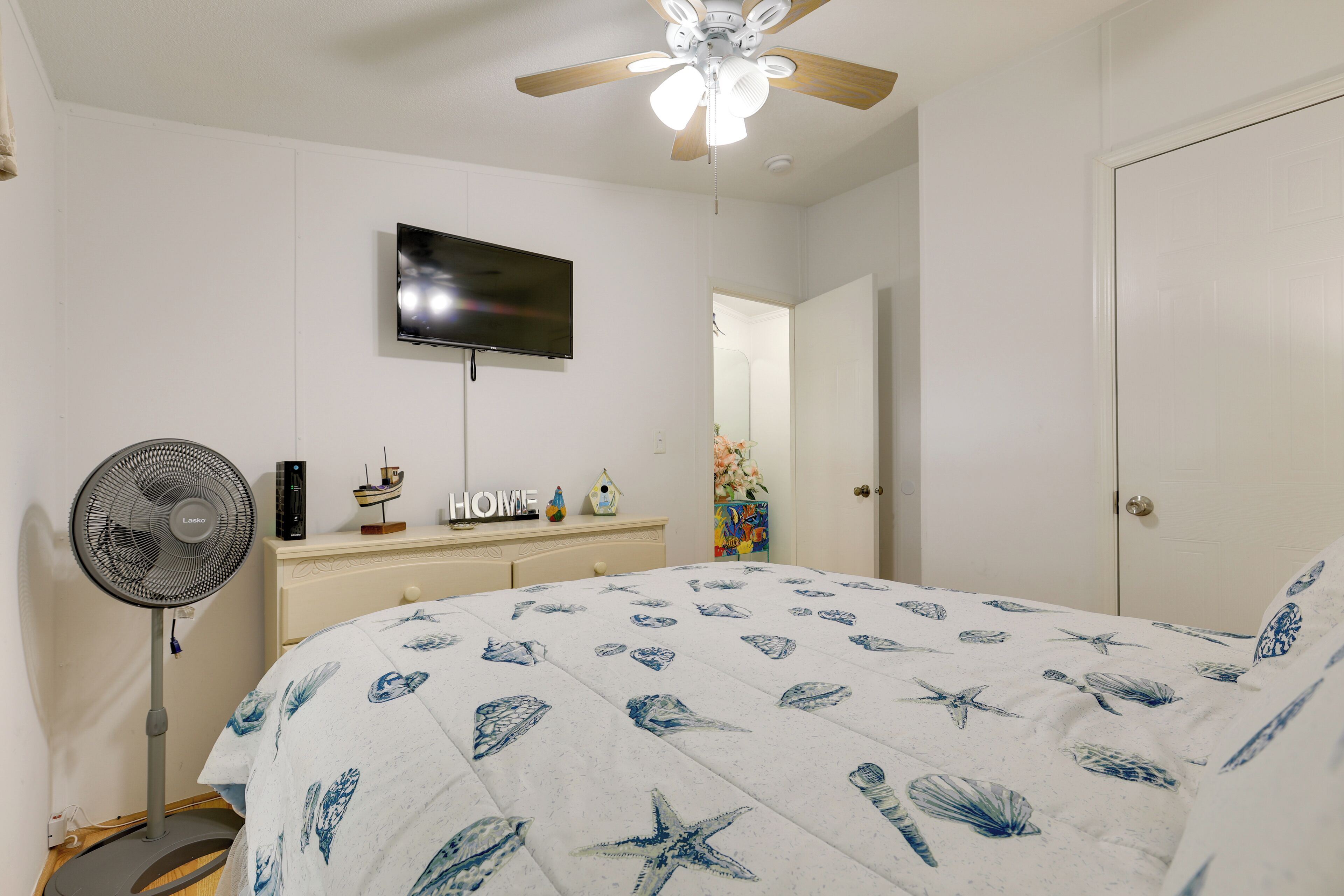 Une chambre à coucher avec un lit, un ventilateur de plafond, une télévision et une commode.