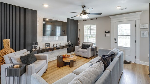 A modern living room with a sofa, coffee table, and a ceiling fan. - Steps to Boardwalk & Beach! Stylish Biloxi Home (Biloxi)