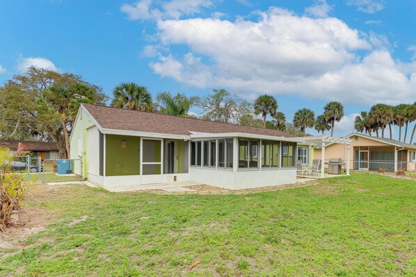 A single-story house with a covered porch, a fenced yard, and a clear sky.