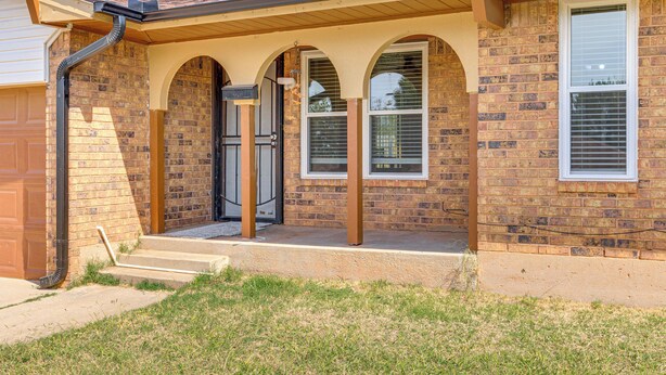 A two-story brick house with a front porch, a garage door, and a window with blinds. - 8 Mi to Bricktown Fun: Quiet Family Retreat (Oklahoma City)