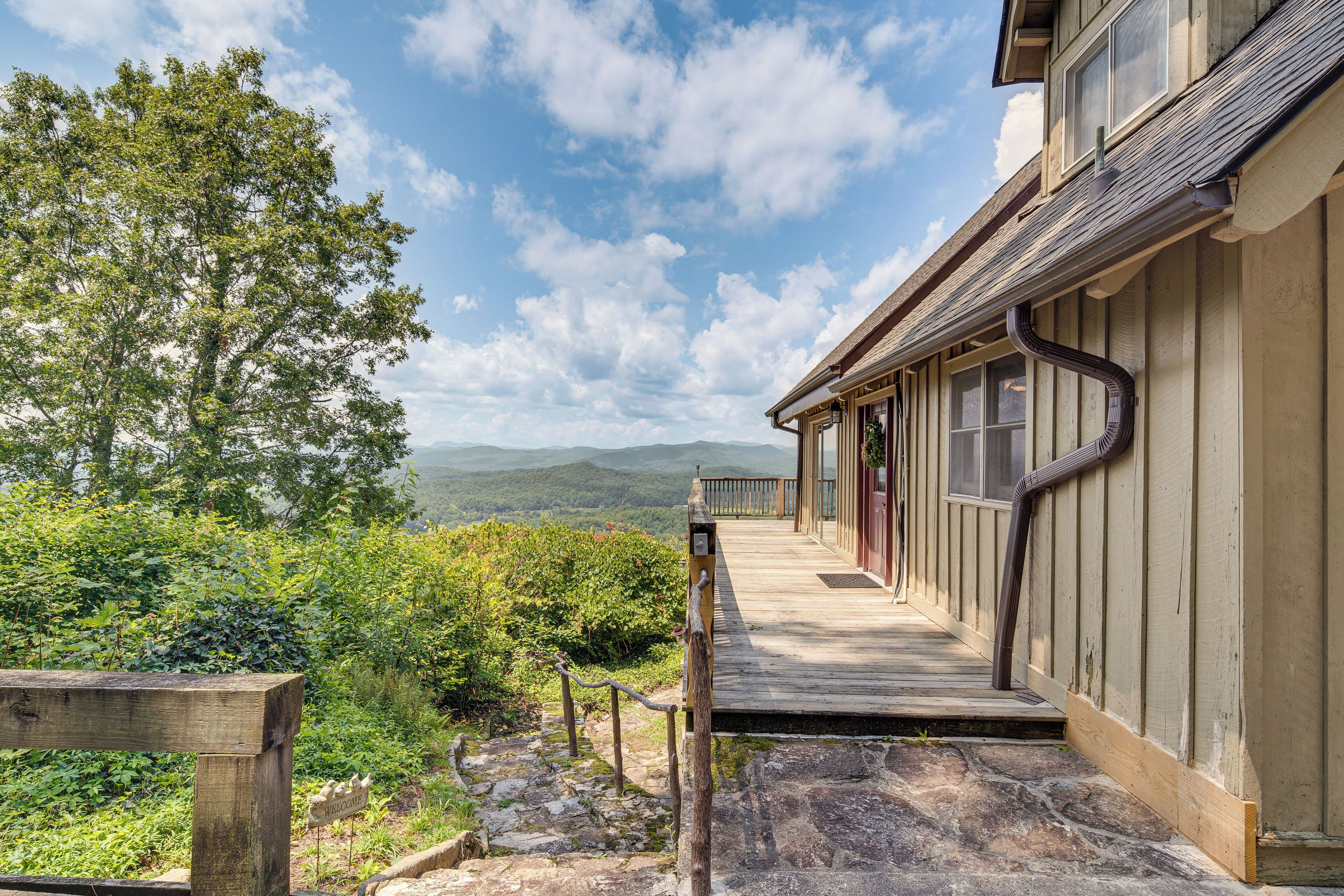 A wooden deck leading to a building with a view of mountains.