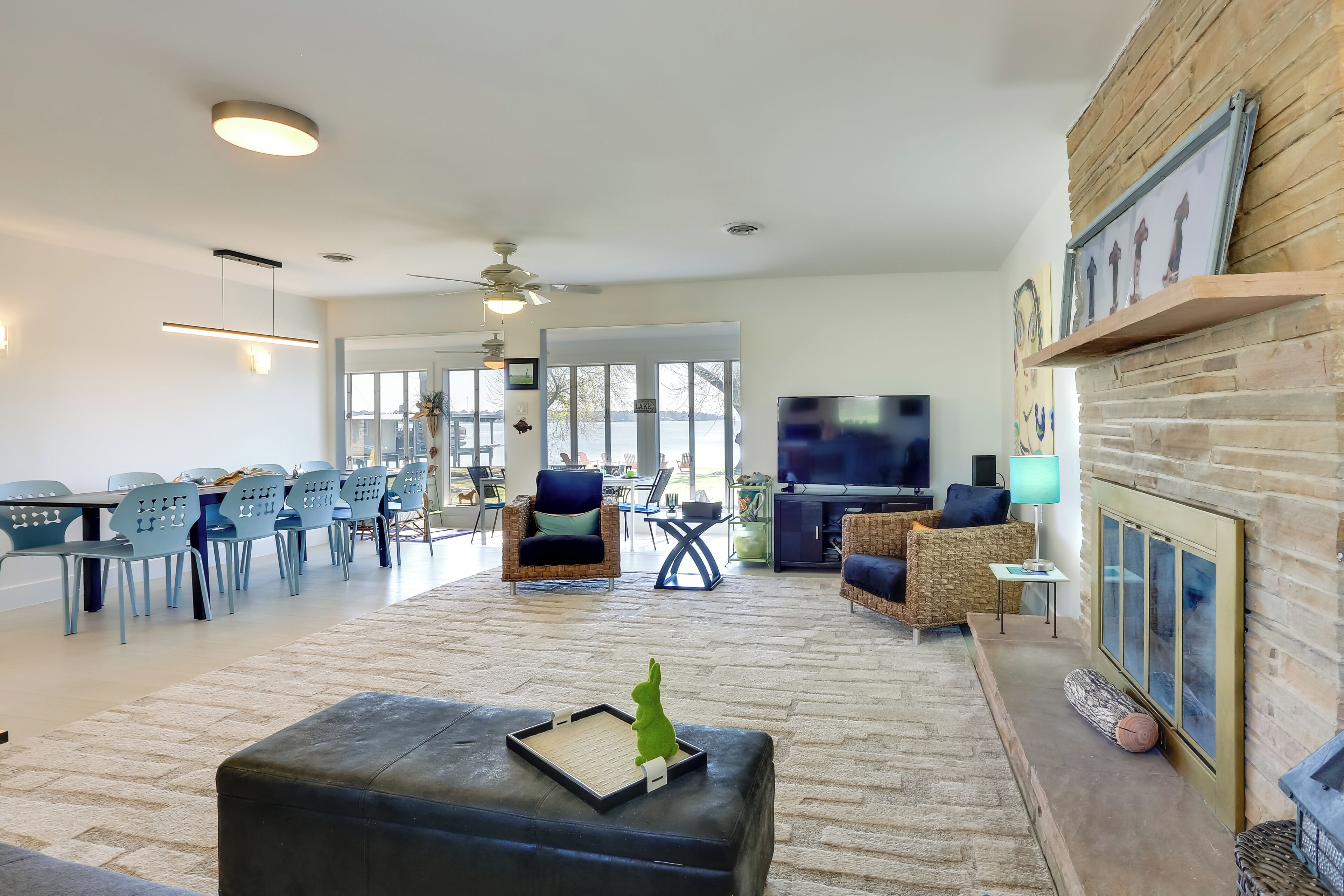 A spacious living room with a fireplace, a television, and a dining area with blue chairs.