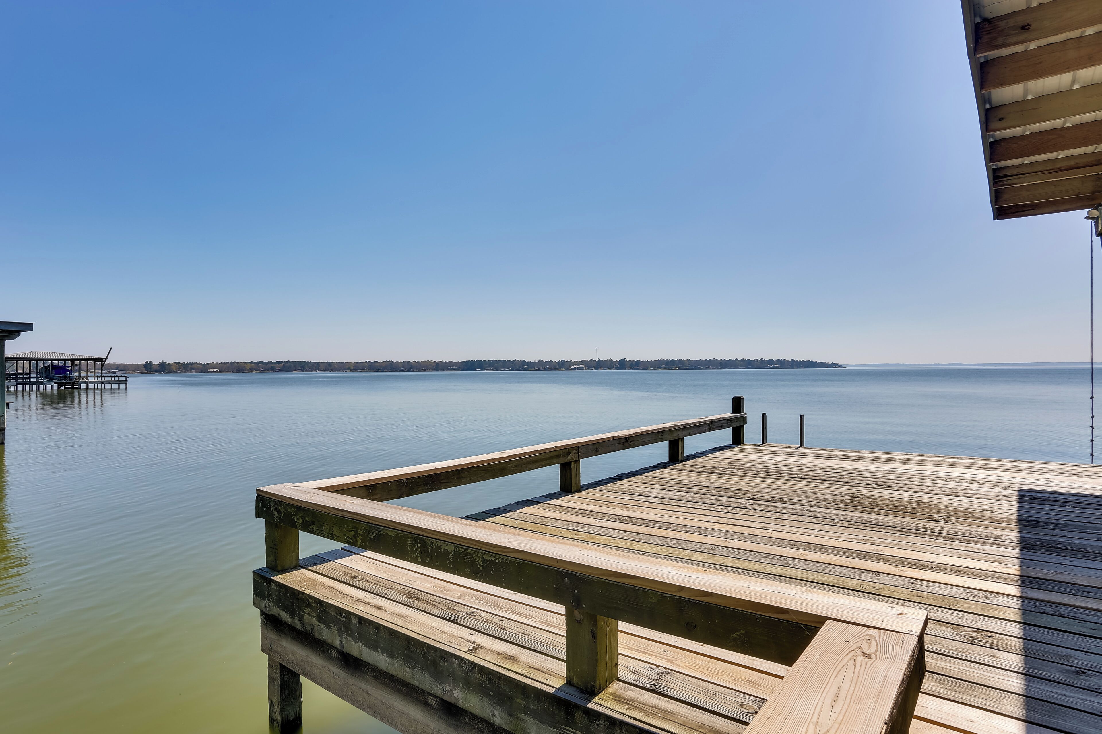 A wooden pier extending into calm water with a clear sky above.