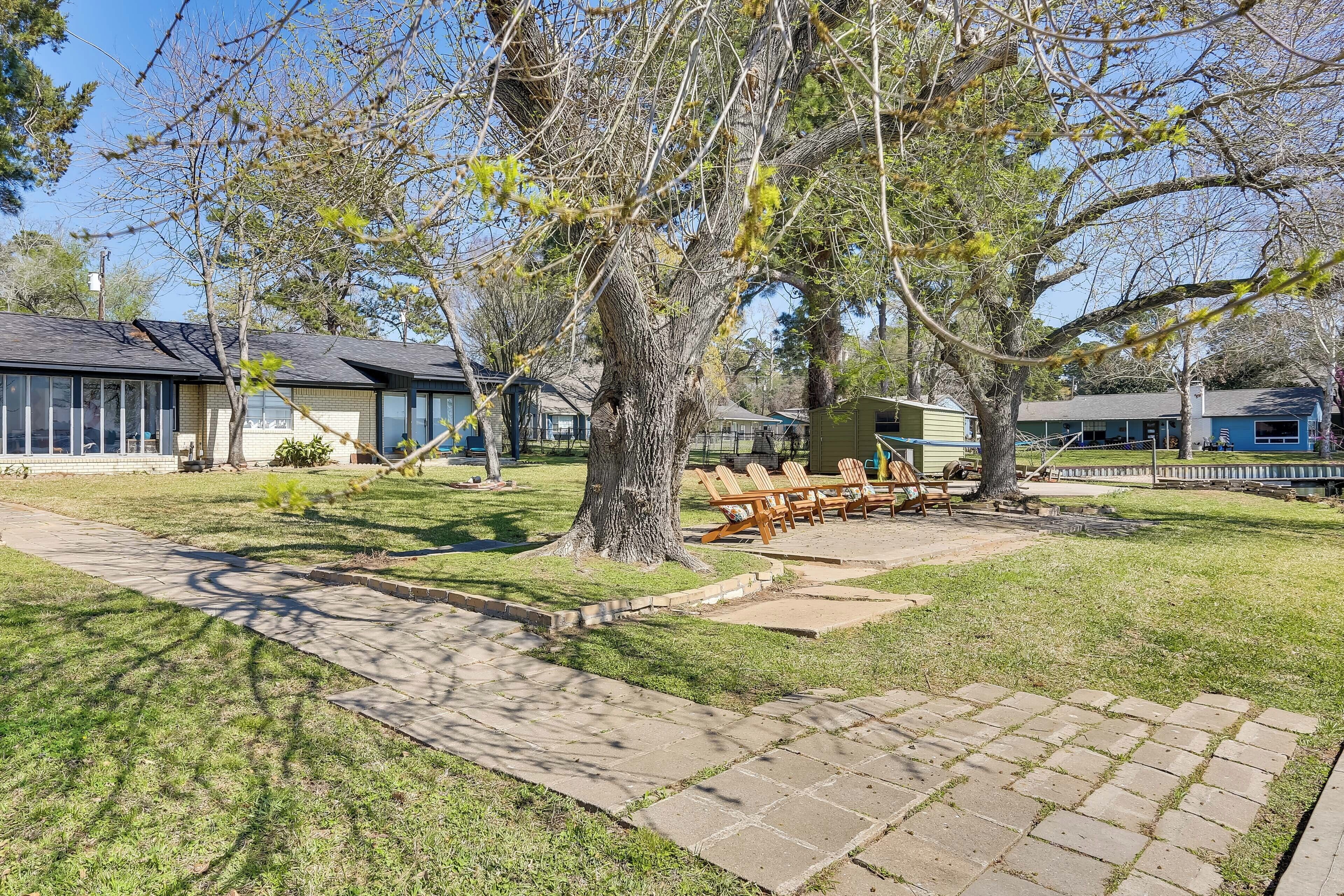 A park with a large tree, a paved walkway, and outdoor seating.
