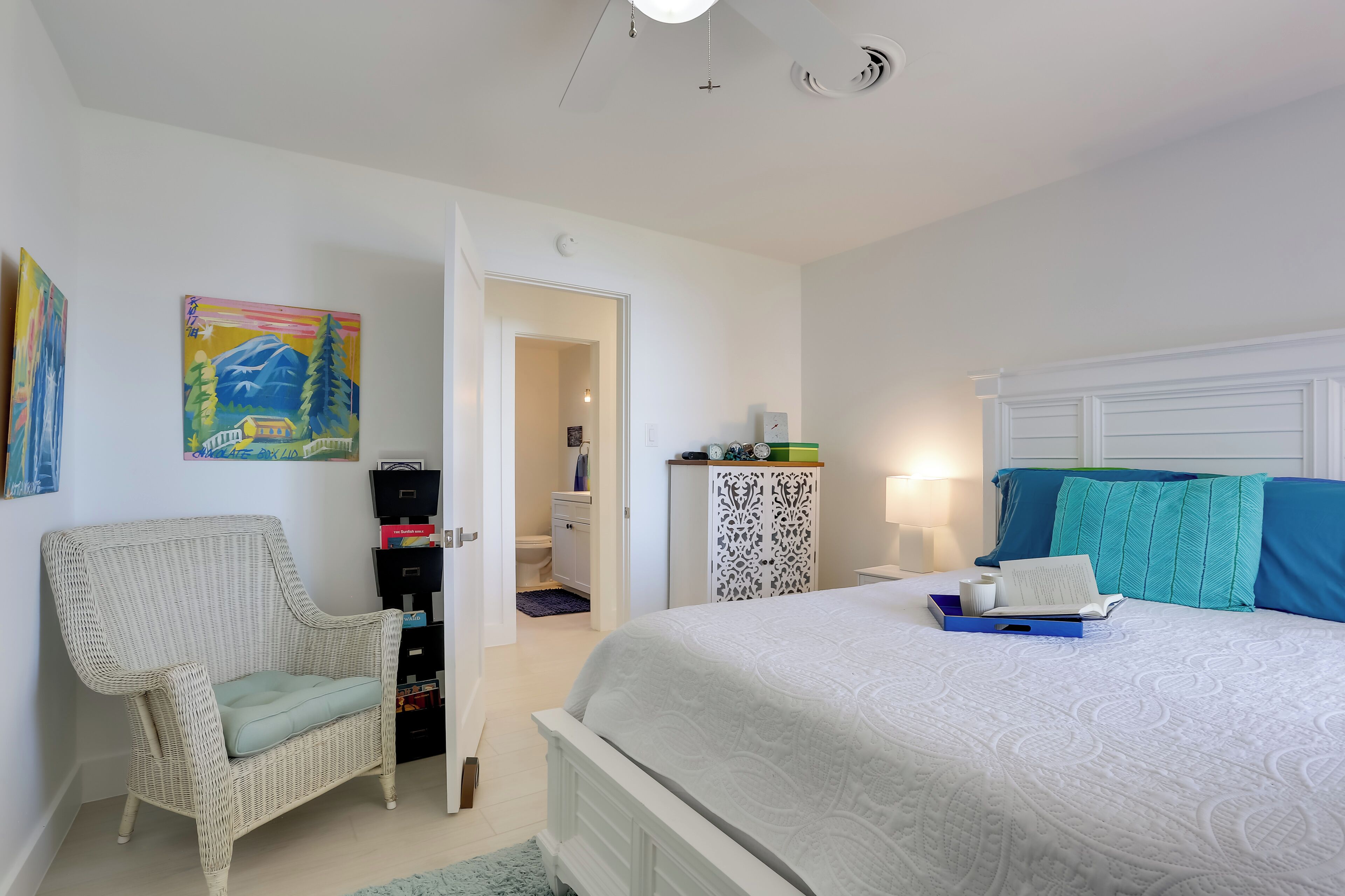 A bedroom with a bed, a chair, a wardrobe, and a painting on the wall.
