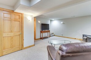 A living room with a wooden door, a glass coffee table, a leather sofa, a TV, and a wooden cabinet.