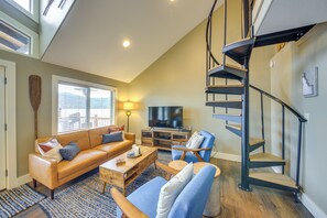 A living room with a sofa, coffee table, TV, and a spiral staircase.