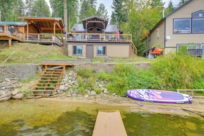 A cabin with a deck, a dock, and a paddleboard.