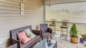 A covered patio with wicker furniture, a ceiling fan, and a large window overlooking a balcony. - Screened Porch + Pool Access: Longs Golf Getaway (Longs)