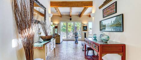 Un couloir avec un plafond en bois, un grand miroir et une table ornée d’objets décoratifs.