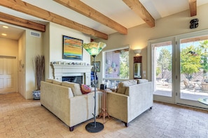 A living room with two sofas, a fireplace, a large window, and a ceiling with exposed beams.