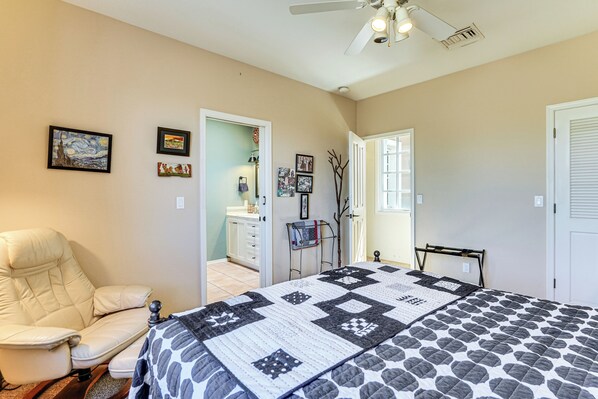 A bedroom with a bed, a chair, a ceiling fan, and a door leading to another room. - Tubac Hacienda in Golf Resort Near Art Village! (Tubac)
