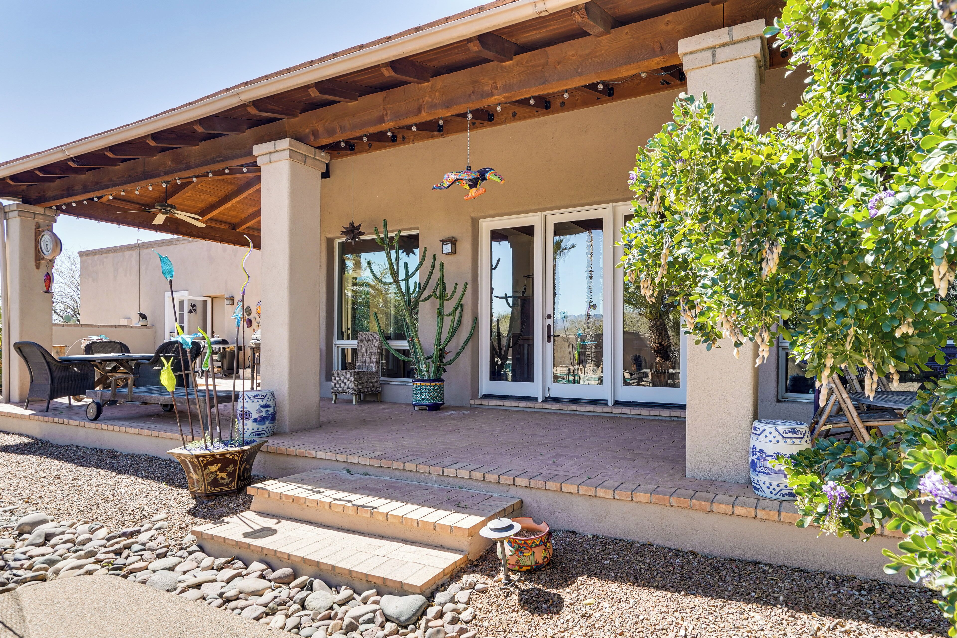 A covered patio area with outdoor furniture, a cactus, and a potted plant.
