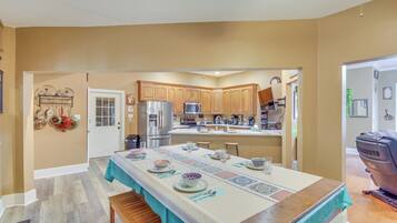 A kitchen with wooden cabinets, a stainless steel refrigerator, and a dining table set with plates and glasses.
