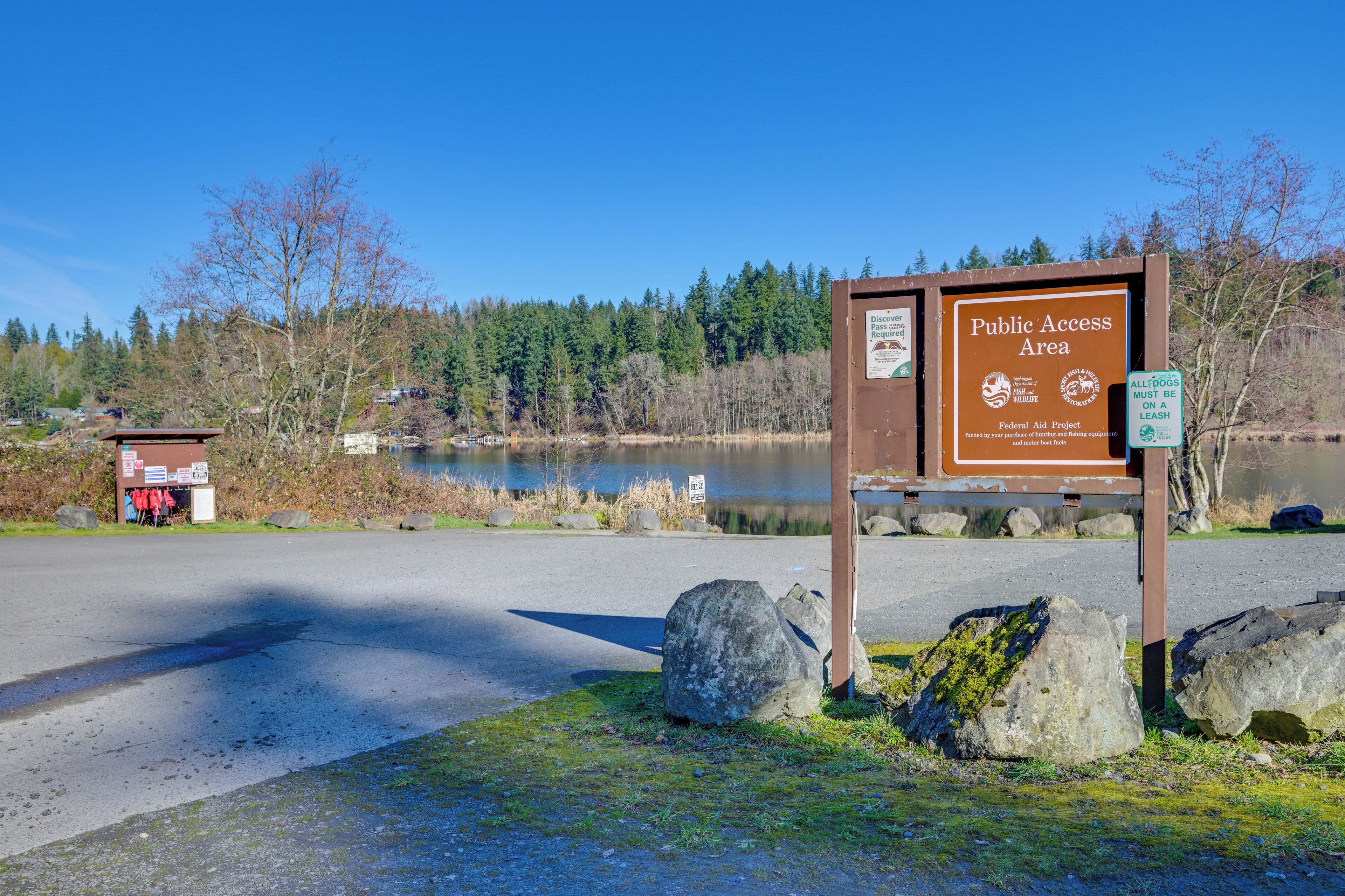 A public access area sign near a lake with a wooden structure in the background.